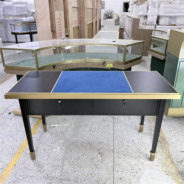 Luxury jewelry consultation table with matte black lacquer body, brushed brass trim, blue velvet presentation surface, and dual lockable drawers for private jewelry viewing — Shangyuan Display